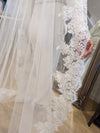 "Close-up of a Mantilla wedding veil made of Alençon/French lace. The veil features an ornate, floral lace design with a scalloped edge, creating an elegant and traditional bridal look."