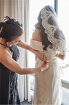 Bride wearing a cathedral-length lace mantilla veil, flowing behind her wedding gown