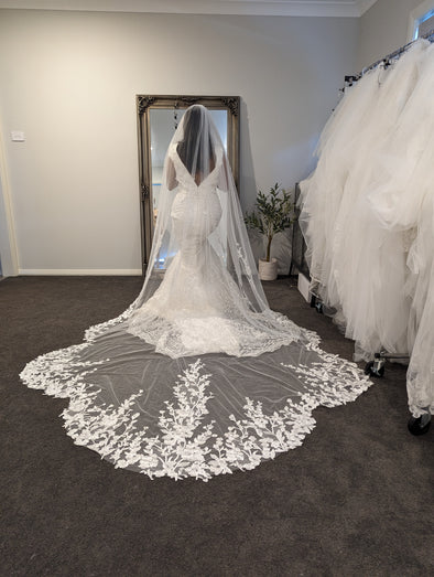 Bride wearing the ALLIE cathedral-length wedding veil with scalloped lace edge and beaded trim from comb to lace.