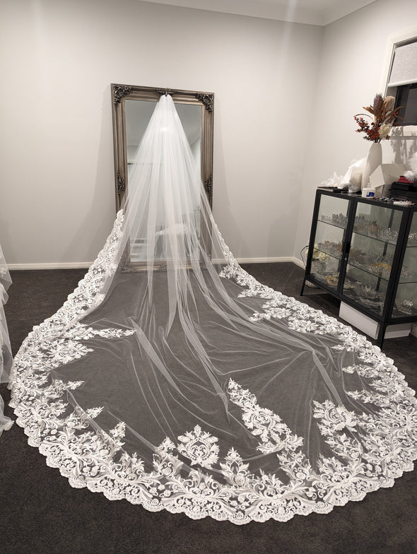 Back view of a bride wearing the OLGA veil, displaying the flowing blusher and intricate lace patterns.
