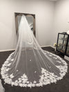 "Back view of a bride wearing the INEZ veil, displaying the flowing cathedral length and detailed lace accents."