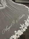 Bride wearing cathedral-length lace-trimmed wedding veil with Mother Mary embroidery
