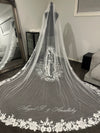 Bride wearing cathedral-length lace-trimmed wedding veil with Mother Mary embroidery