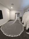 "Bride holding the edge of the ELIKA beaded lace veil, emphasizing the intricate craftsmanship."