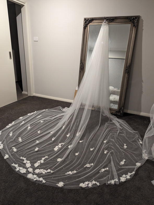 Bride wearing the SAMANTHA cathedral-length wedding veil, featuring 3D floral petals embellished with pearls and lace appliqués.
