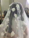Back view of a bride in a wedding gown with the NADIA cathedral veil, featuring a cascading floral pattern.