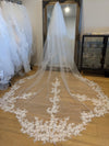 A close-up view of a lace veil adorned with intricate sequined patterns. The delicate fabric features floral designs interwoven with tiny, shimmering sequins, giving it a sparkling and elegant appearance