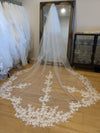 "Close-up of a delicate lace veil with sequins. The veil features intricate floral patterns and a touch of sparkle from the sequins."