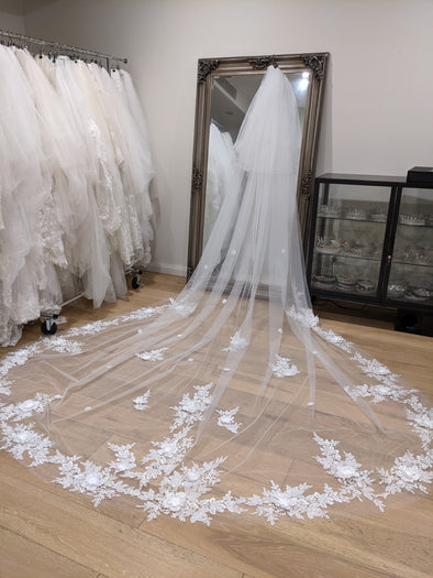 "Bride wearing the AVA cathedral-length wedding veil, featuring 3D floral lace appliqués along the edge."