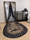 Elegant black mantilla bridal veil with floral lace appliqués and a dramatic sheer tulle train