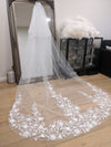 Bride wearing the SUZIE cathedral-length wedding veil, featuring 3D floral lace appliqués along the edge.